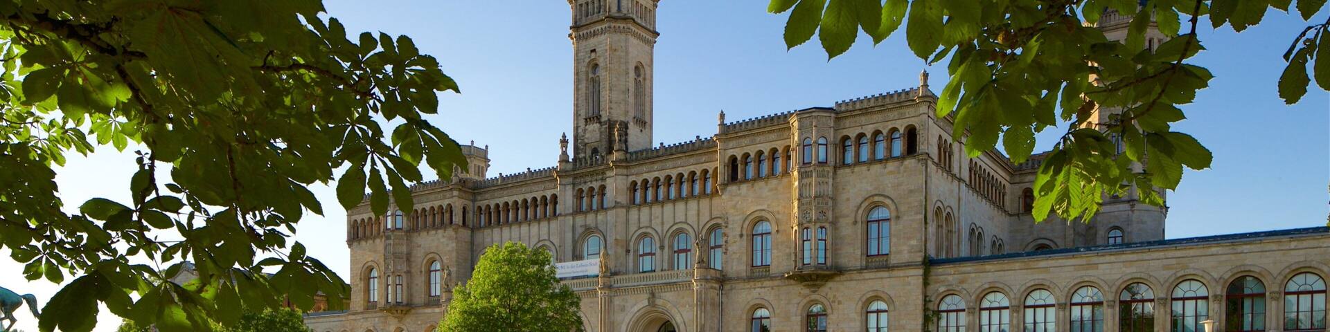 A historic building with a prominent tower, surrounded by a well-maintained lawn and trees.