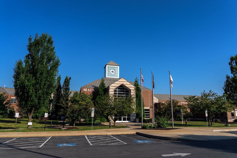 A building with a clock tower, American flags, and a parking lot.
