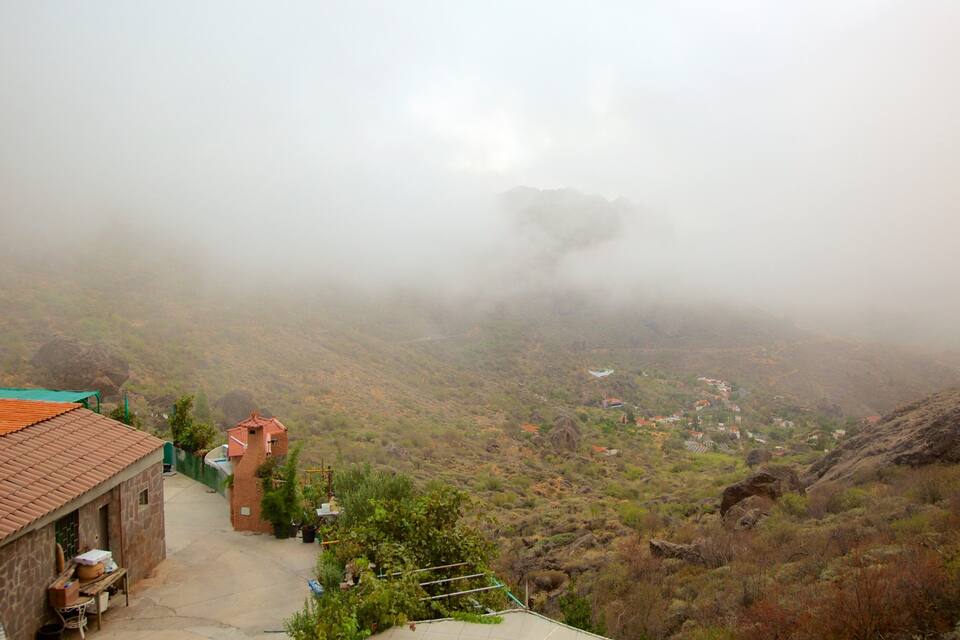A foggy mountainous village with terraced fields and traditional houses.