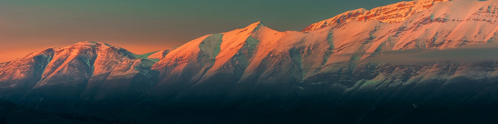 Cordillera de montañas con picos nevados y cielo despejado.