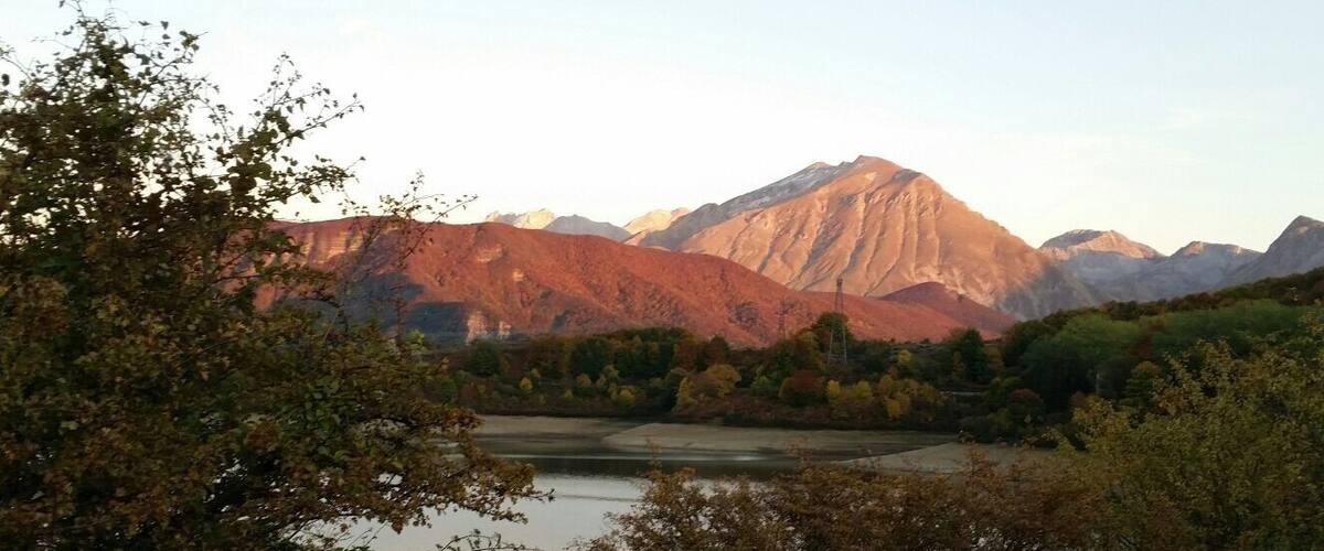 A mountainous landscape with a lake and dense forest.