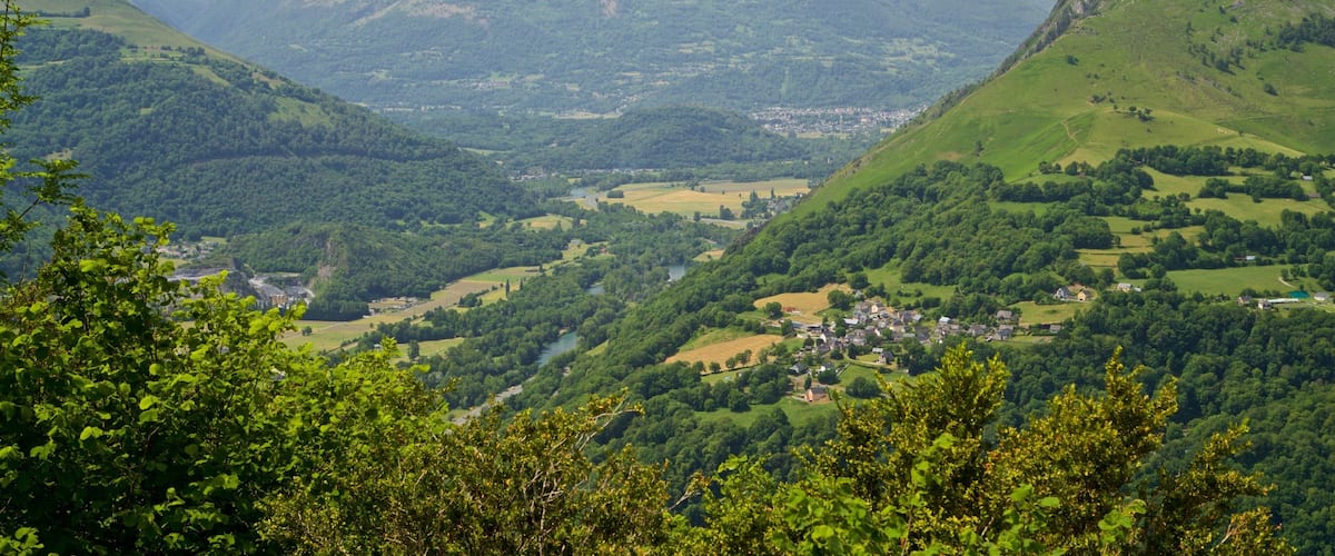 A valley with a river, surrounded by mountains and greenery.