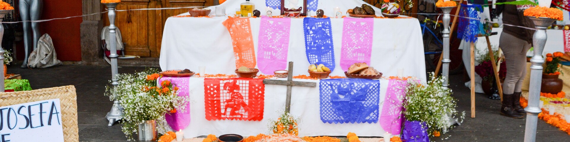 A traditional altar with marigold flowers, a cross, and a sign reading "Josefa Guez 38/2-Mar-1829".