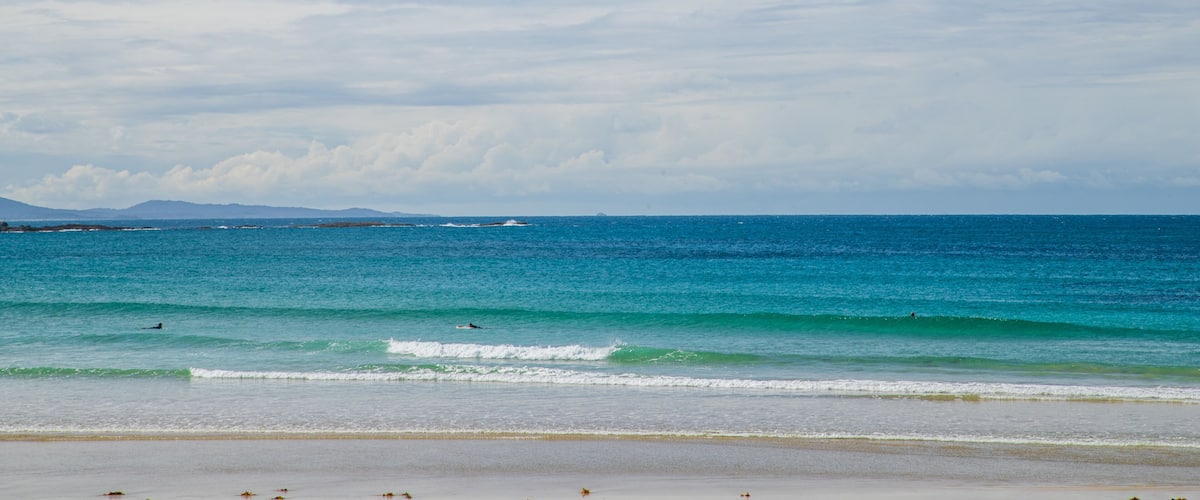 Woolgoolga Beach which includes general coastal views and a sandy beach