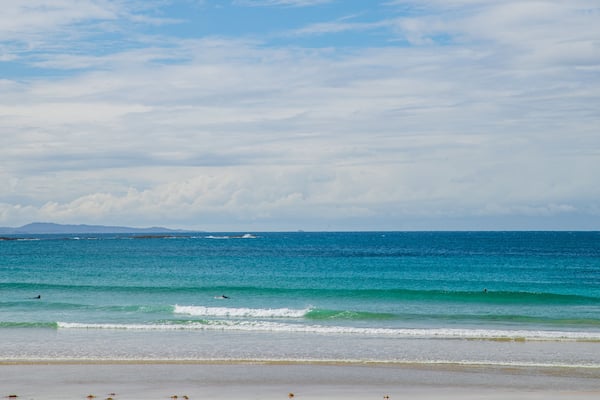 Woolgoolga Beach which includes general coastal views and a sandy beach