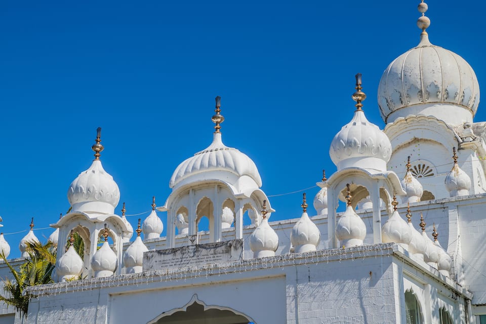 Un templo blanco con múltiples cúpulas y detalles arquitectónicos intrincados, sobre un cielo azul despejado.