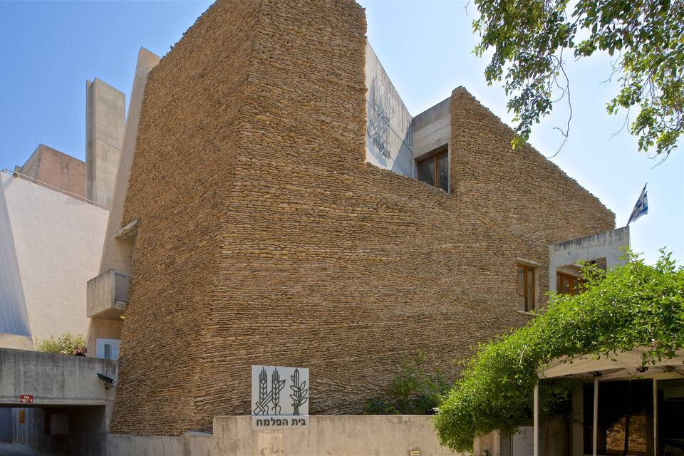 A building with a textured stone facade and a sign with Hebrew script.