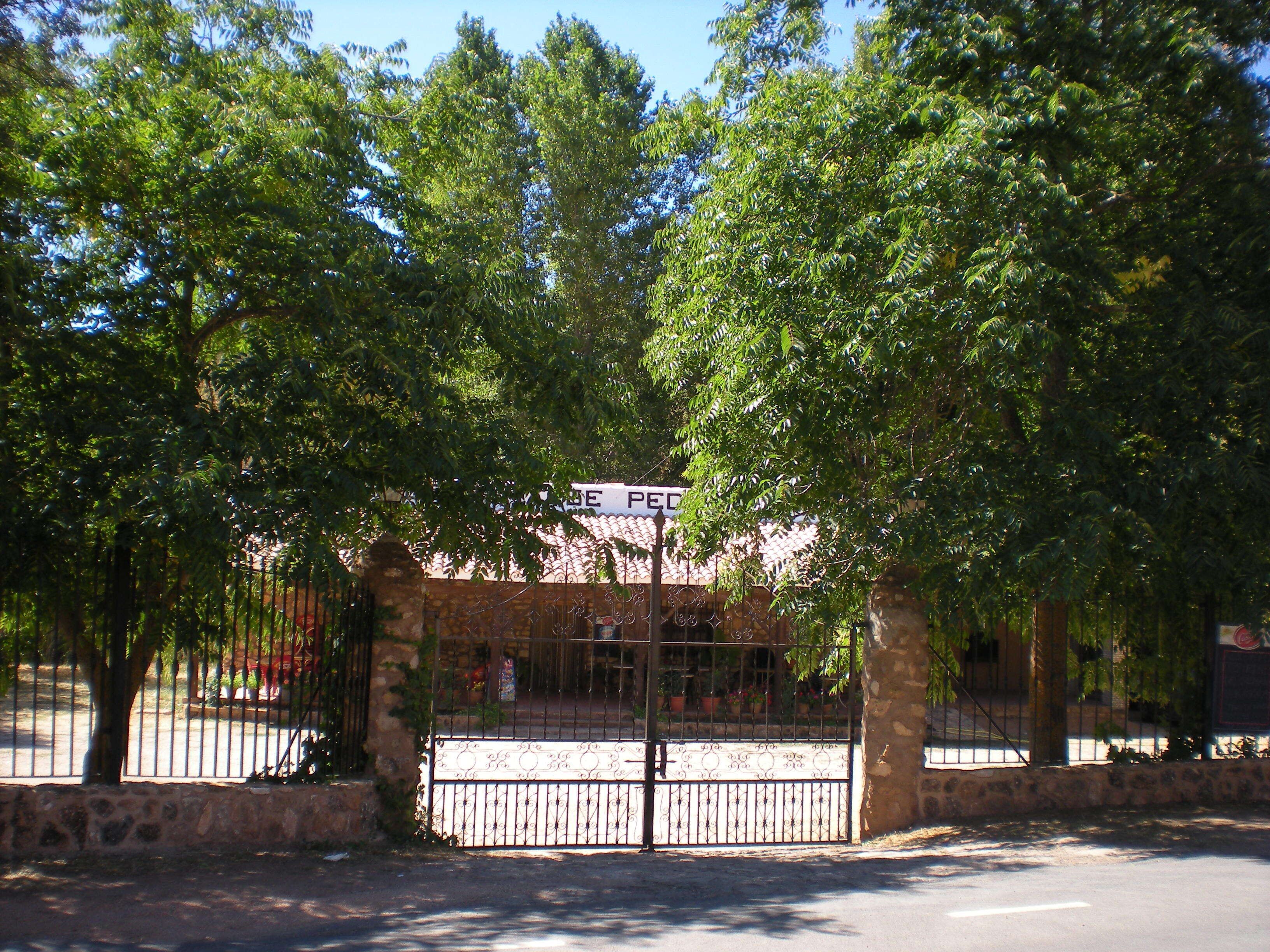 A gated entrance with a sign, surrounded by trees and a stone wall.