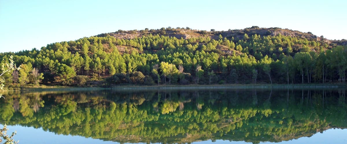 A calm lake with a reflection of a forested hill.