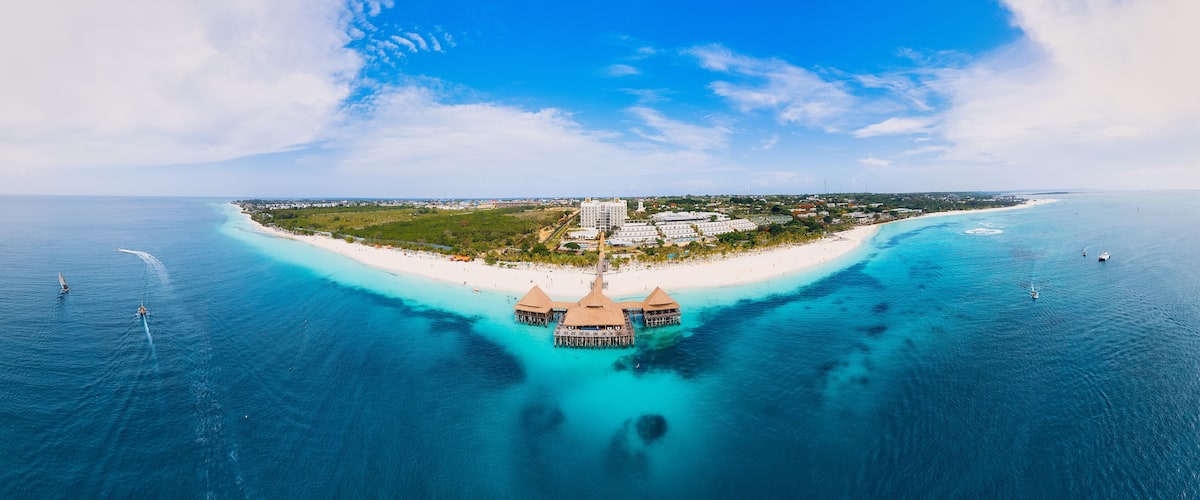 A tropical island with a white sandy beach, clear turquoise waters, and overwater bungalows.