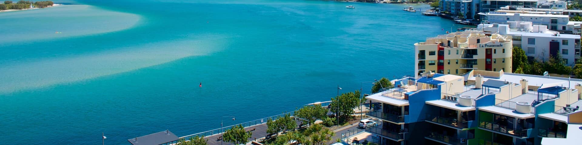 A coastal city with turquoise waters, modern buildings, and a clear sky.