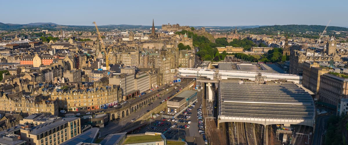 Panoramic aerial image of Edinburgh cityscape at Sunrise featuring Waverley Railway Station.