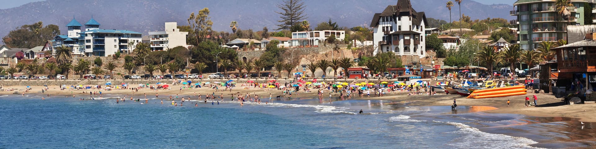 A coastal town with a beach, ocean, and mountains in the background.