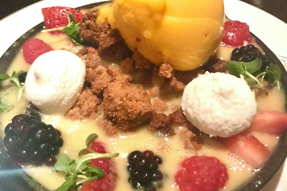 Un postre con mango, bayas y una base cremosa.
