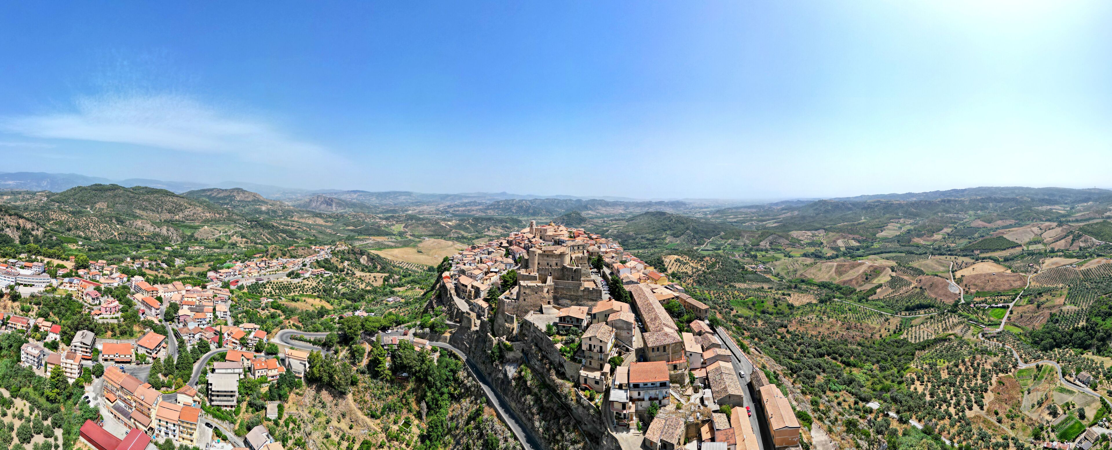 A town built on a hillside with a winding road and surrounding hills.