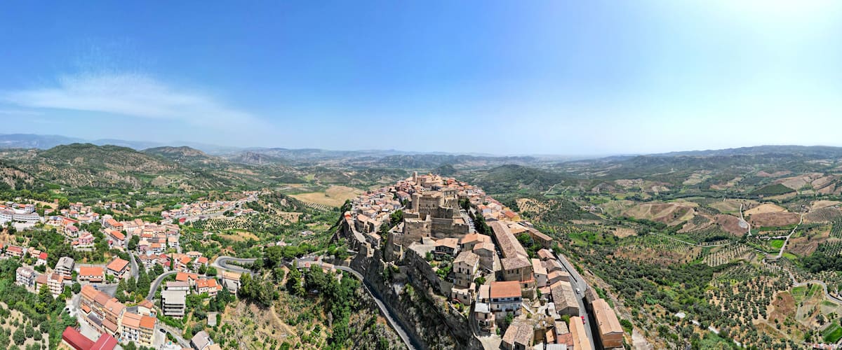 A town built on a hillside with a winding road and surrounding hills.