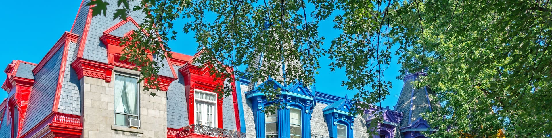 Colorful Victorian-style houses with intricate architectural details and lush green trees.