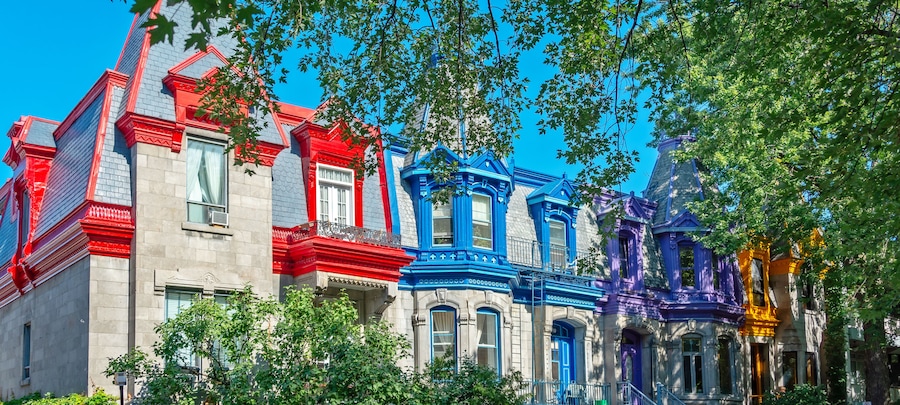 De jolies maisons de style victorien aux couleurs vives, dotées de détails architecturaux complexes et bordées d’arbres verdoyants.