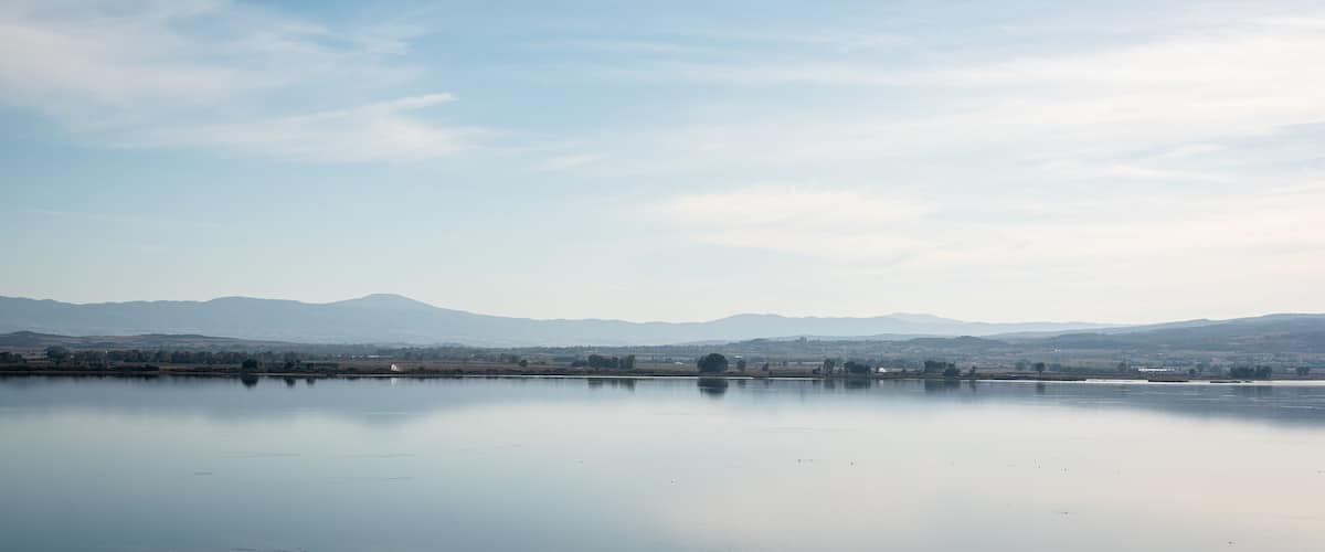 A calm lake with a mountain range in the background.