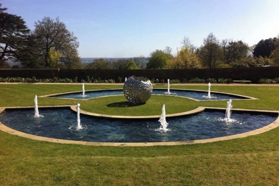 A landscaped garden with a central spherical sculpture surrounded by four fountains.