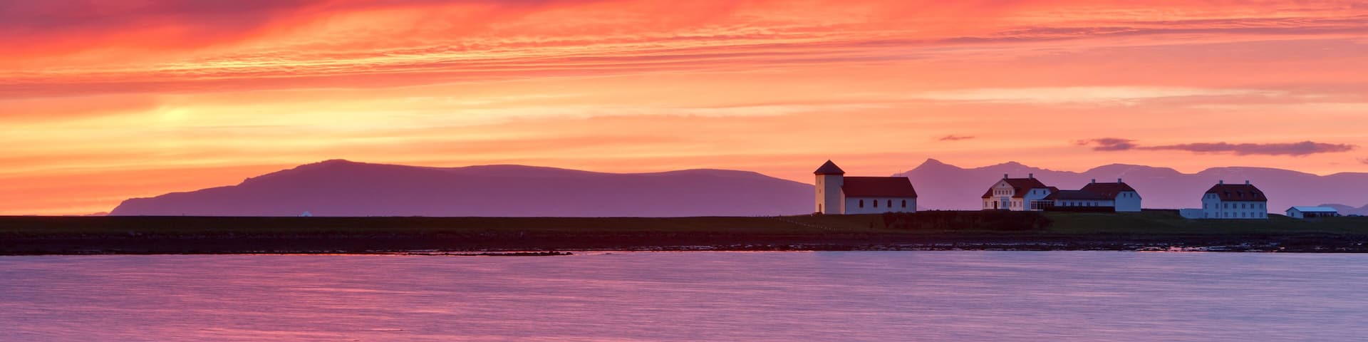 Mountain range and presidents residence building in remote setting at sunset, Bessastadir, Alftanes, Iceland