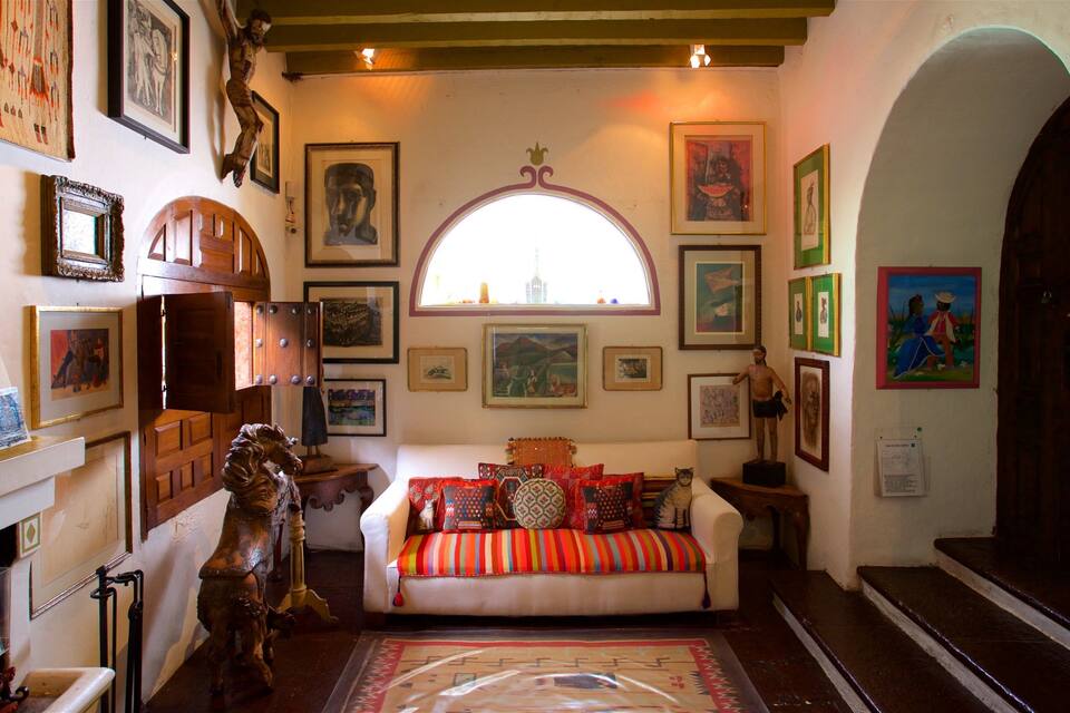 A cozy living room with a sofa, various framed artworks, and a wooden cabinet.