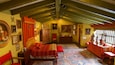 A traditional bedroom with a wooden ceiling, a large bed with red bedding, and various framed pictures and decorations on the walls.