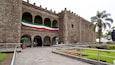 A historic stone building with arched entrances and a large flag.