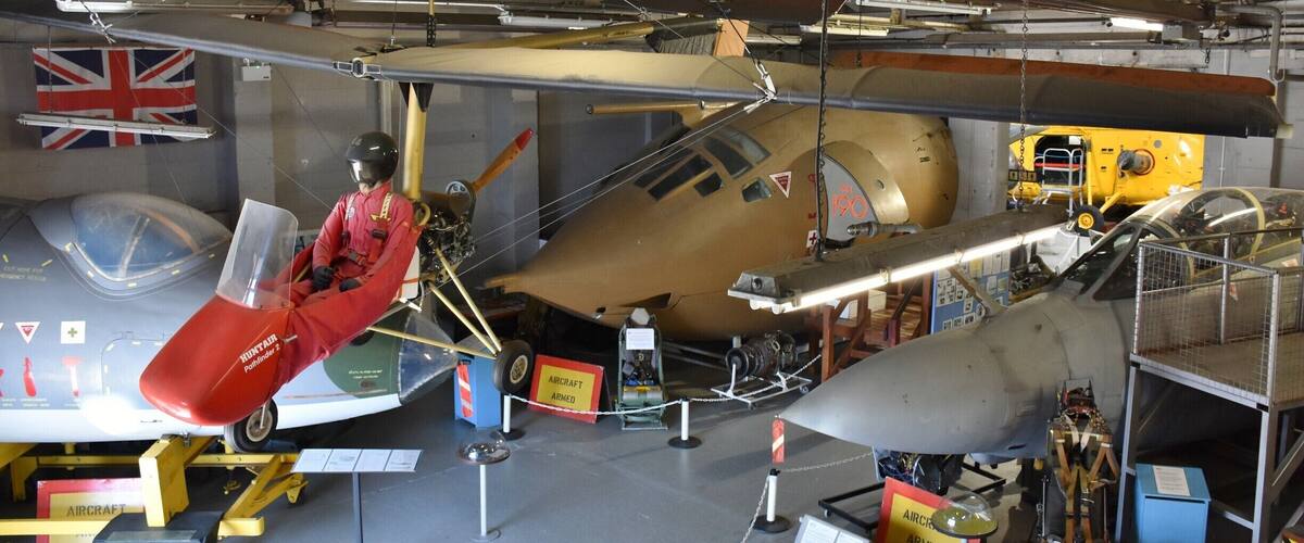 A museum exhibit with a vintage aircraft, a pilot mannequin, and various military memorabilia.