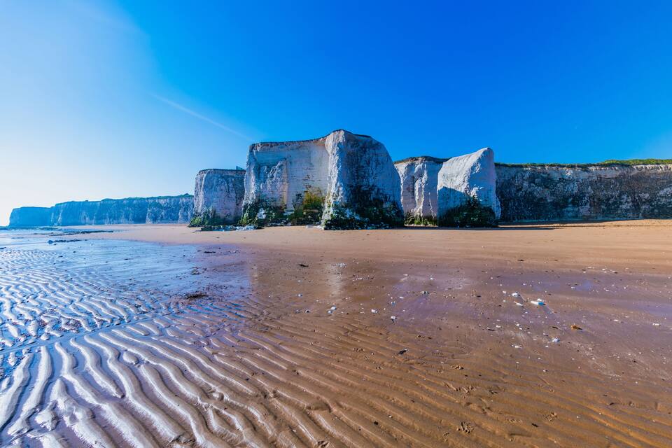 A sandy beach with white rock formations in the background.