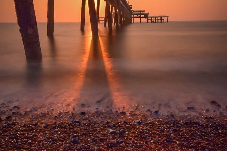 A pebbled beach with a pier extending into the water.
