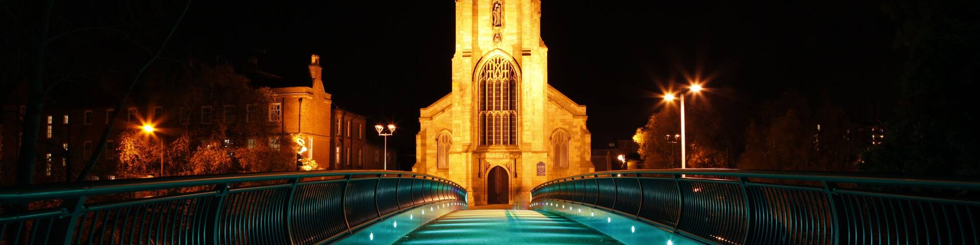 Illuminated modern footbridge leading to st mary's church at night in derby city