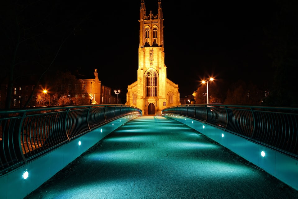 A lit bridge with a church in the background.