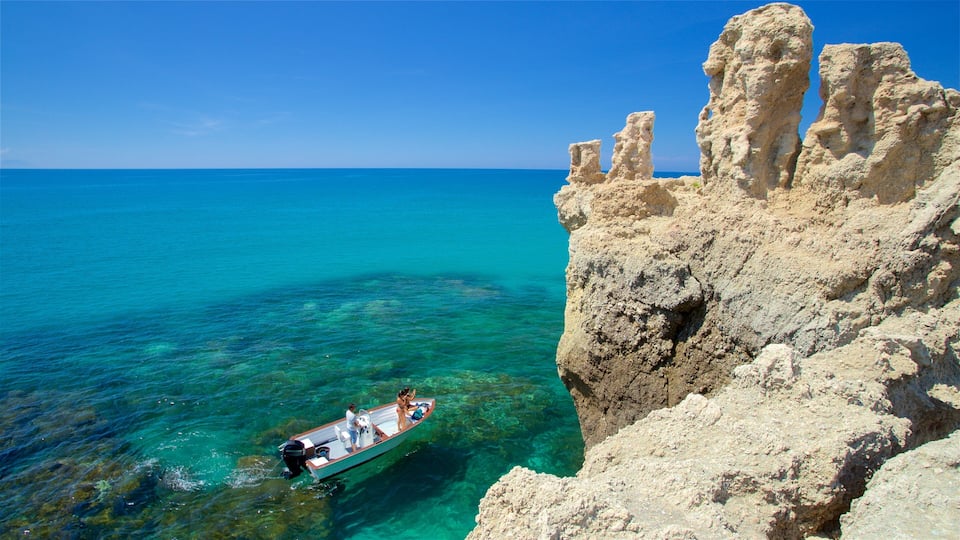 A boat near a rocky coastline with clear turquoise water.
