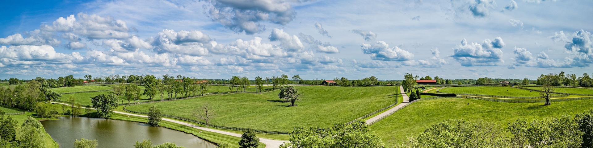 Ein Golfplatz mit Teich, umgeben von grünen Feldern und Bäumen.