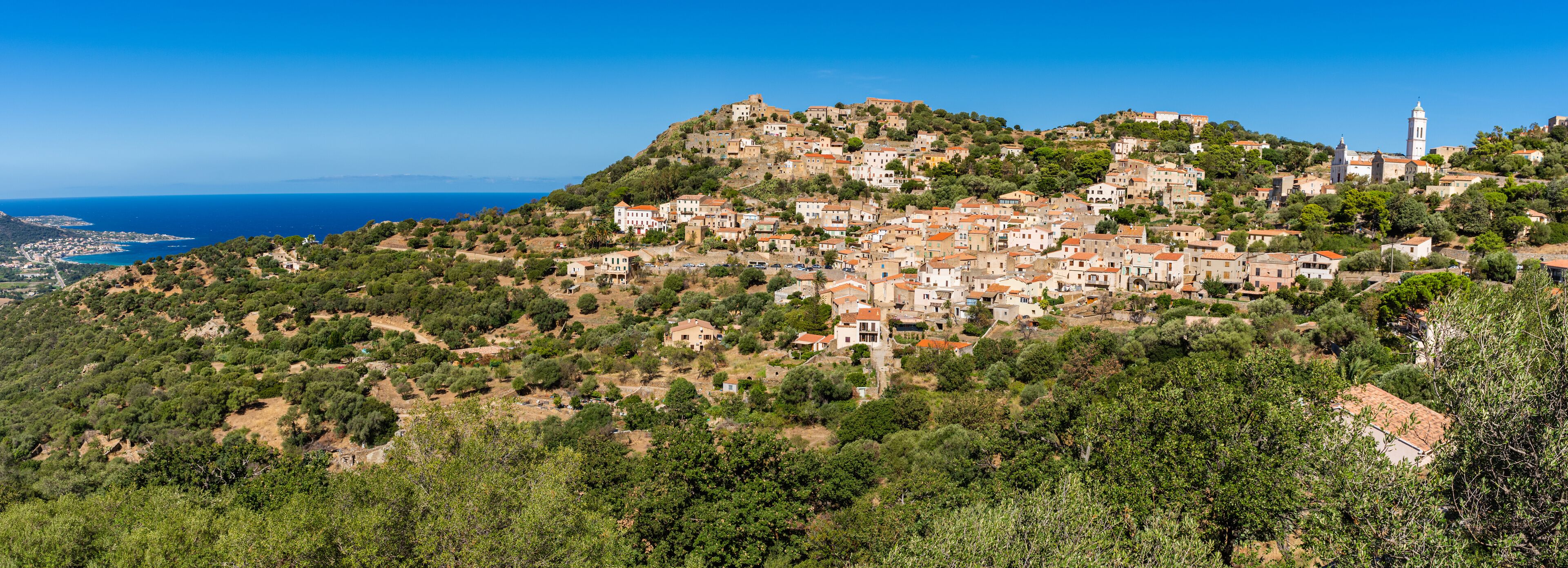 A coastal village with terraced houses on a hillside, overlooking the sea.