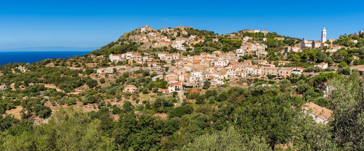 A coastal village with terraced houses on a hillside, overlooking the sea.