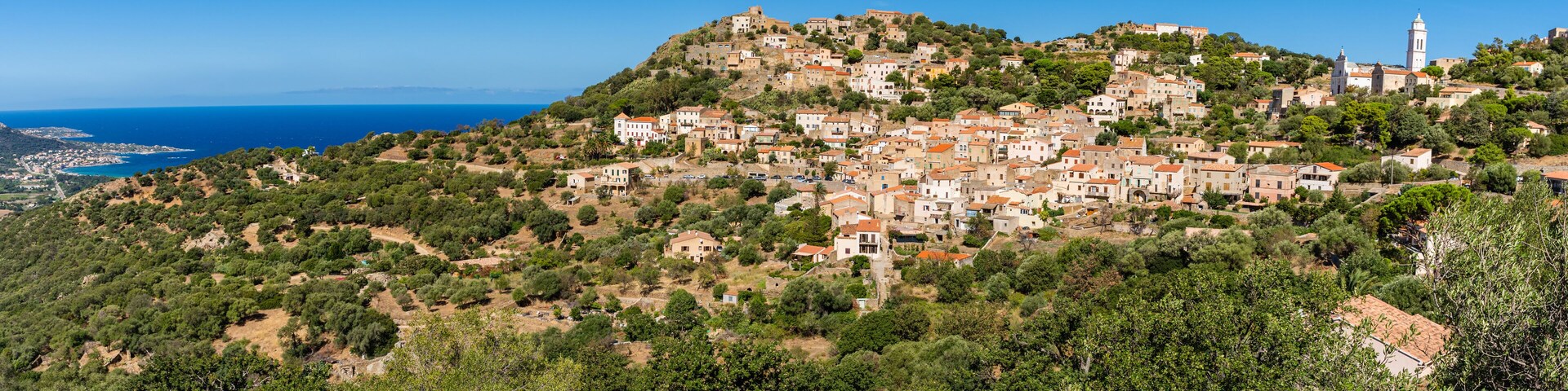 A coastal village with terraced houses on a hillside, overlooking the sea.
