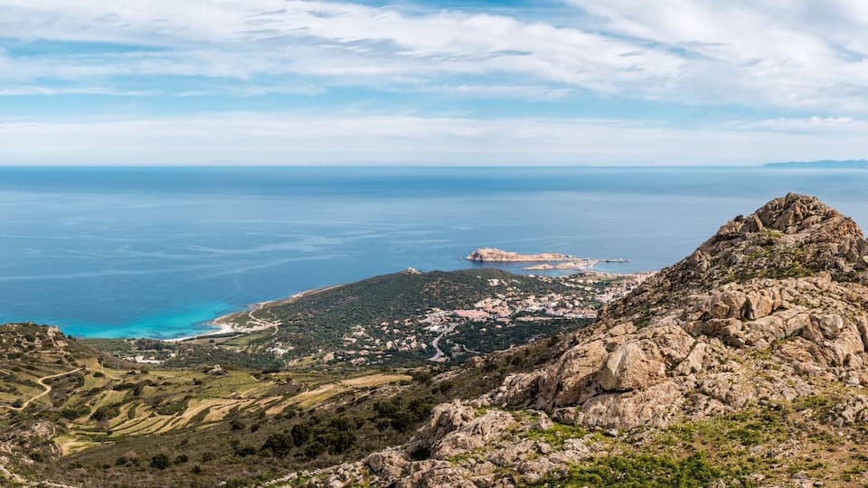 Panoramic view of the coastline of Corsica and the village of Corbara, Bodri beach the red rock of Ile Rousse with Cap Corse in the distance