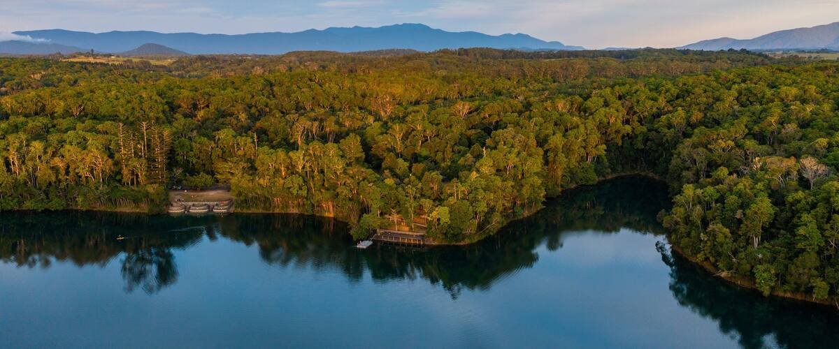 A lake surrounded by dense forest and mountains in the background.