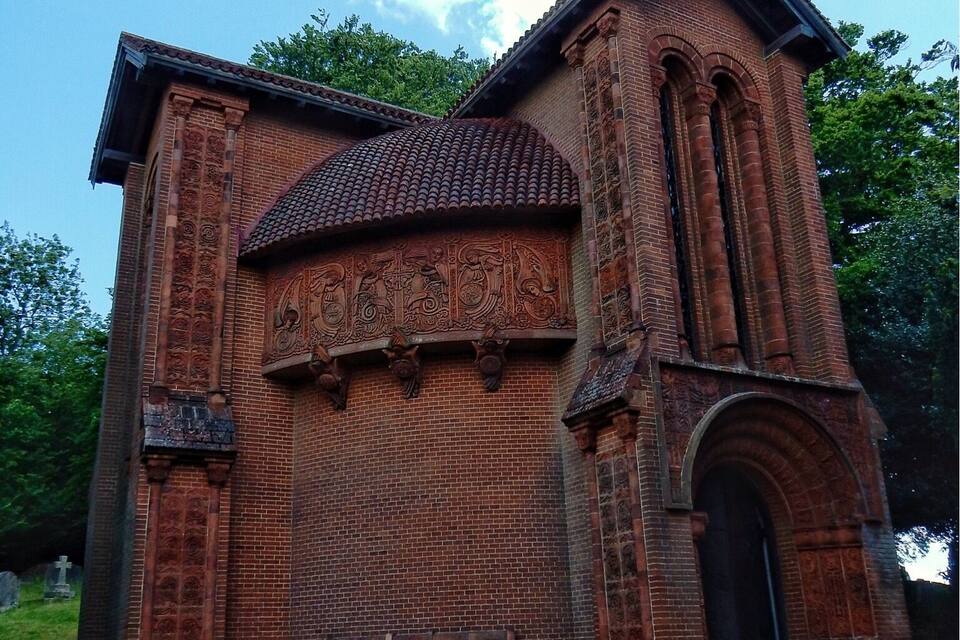 Una església de maó amb detalls escultòrics complexos i teulada d'àmples rajoles.