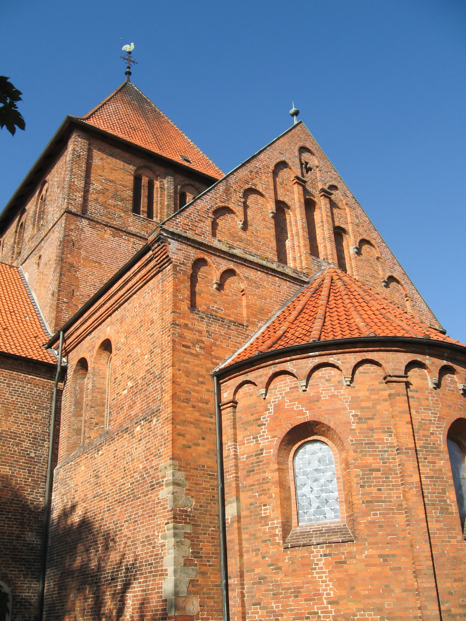 A brick church with a red-tiled roof and arched windows.