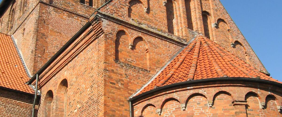 A brick church with a red-tiled roof and arched windows.