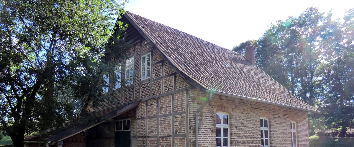 A historic brick building with a sloped roof and a bench in front.