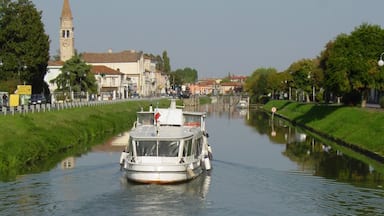 Una barca su un canale con una torre sullo sfondo.