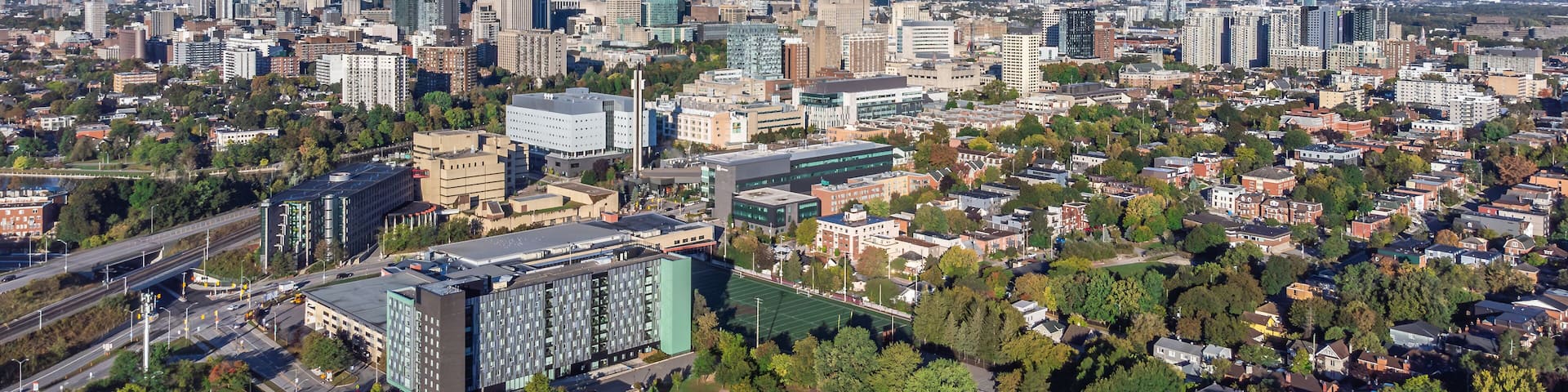 Aerial panoramic view of downtown Ottawa, including University of Ottawa campus, Sandy Hill, Parliament Hill and Peace Tower, Gatineau Park hills in the backdrop, Ontario, Canada (September 2024)