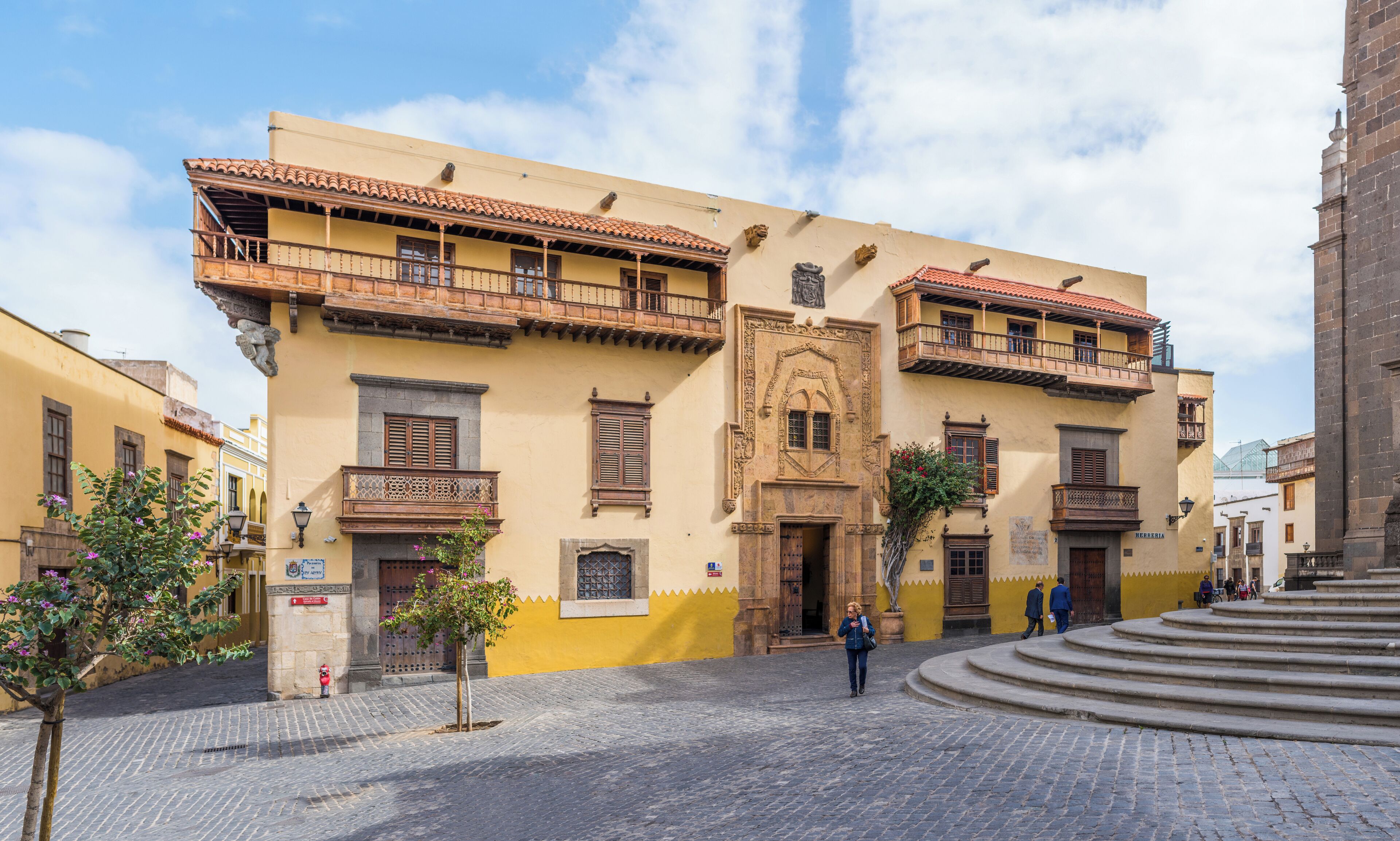 A historic building with ornate balconies and a cobblestone street.
