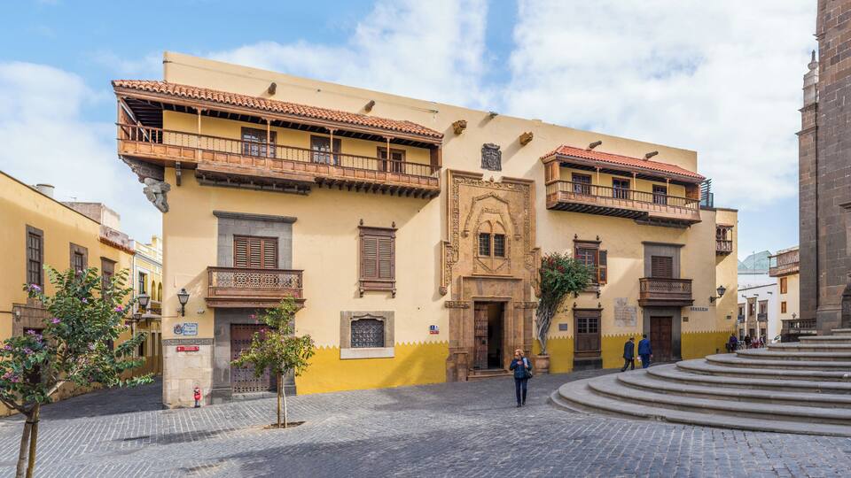 A historic building with ornate balconies and a cobblestone street.