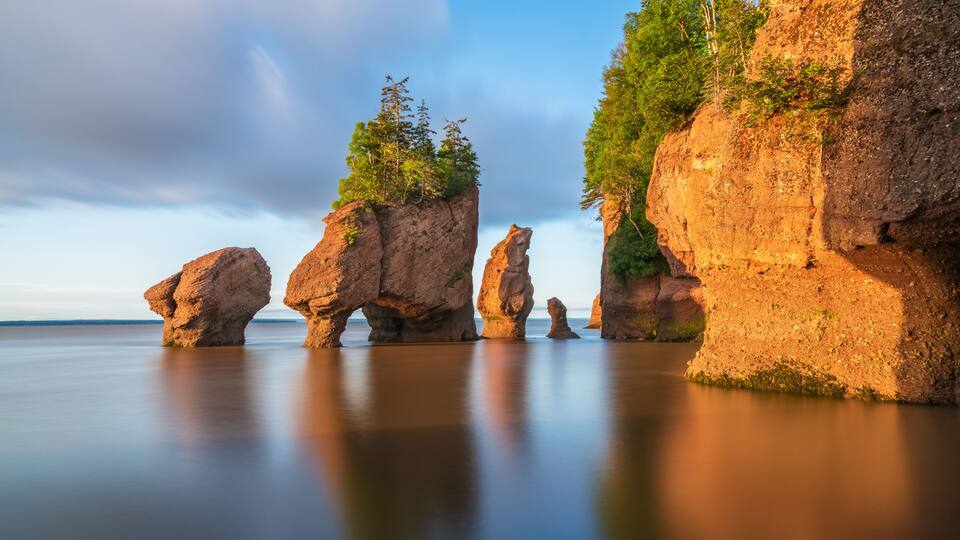 A coastal landscape with prominent rock formations and calm water.