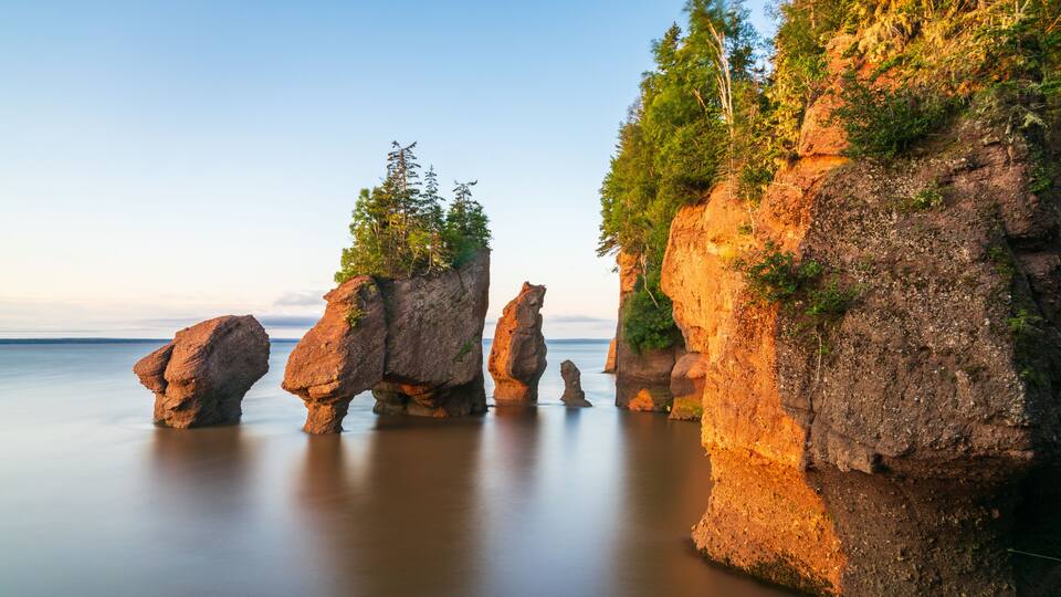 A coastal landscape with prominent rock formations and a calm sea.